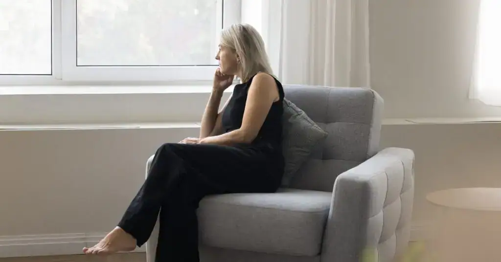 Woman sitting thoughtfully by a window, reflecting on early signs of perimenopause