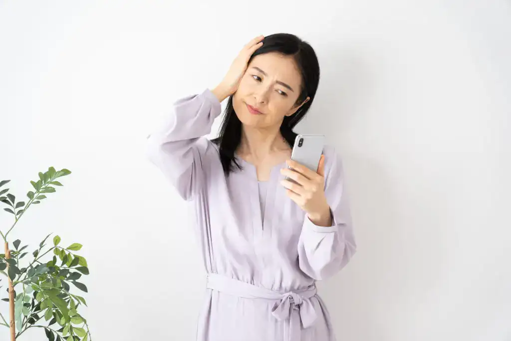 Woman in her early 40s sitting thoughtfully by a window, reflecting on early menopause symptoms